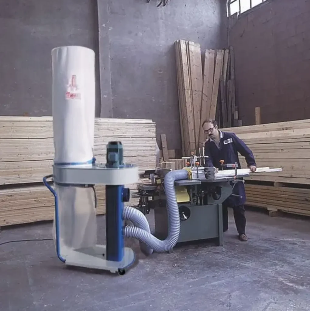 Sistema de extracción industrial de polvo conectado a maquinaria de carpintería en taller de madera